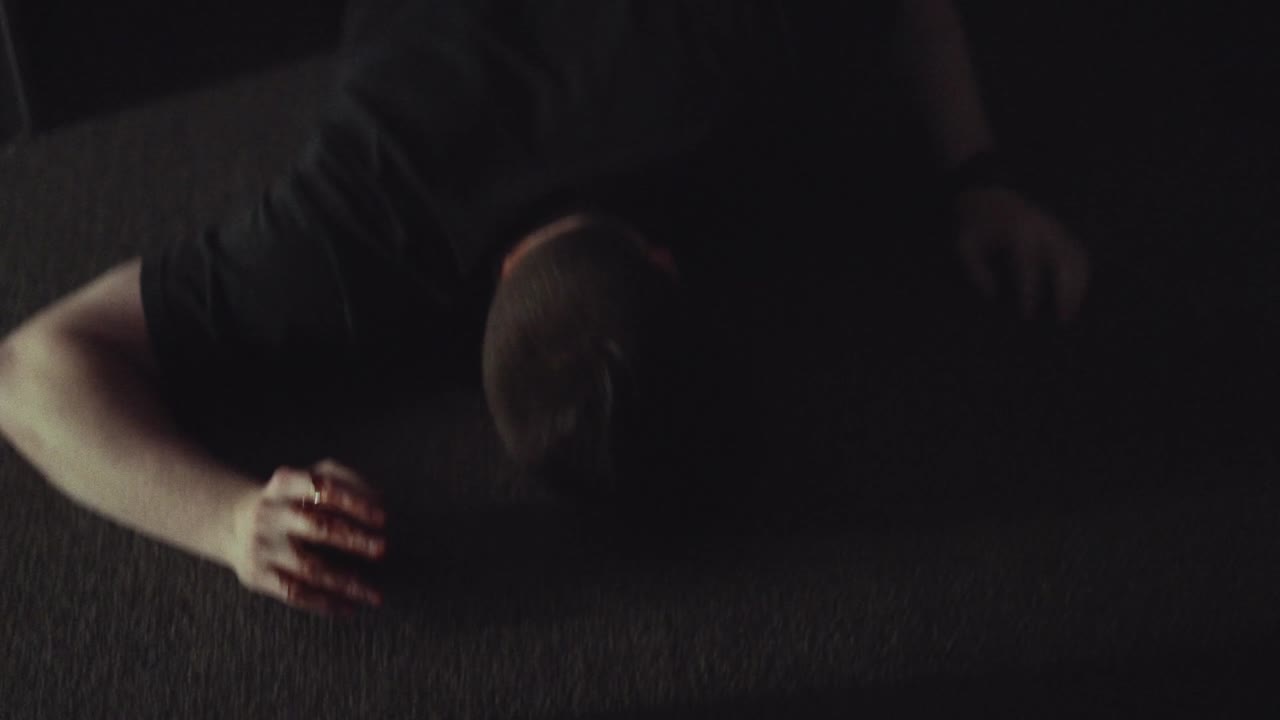 A figure lying on a dark floor