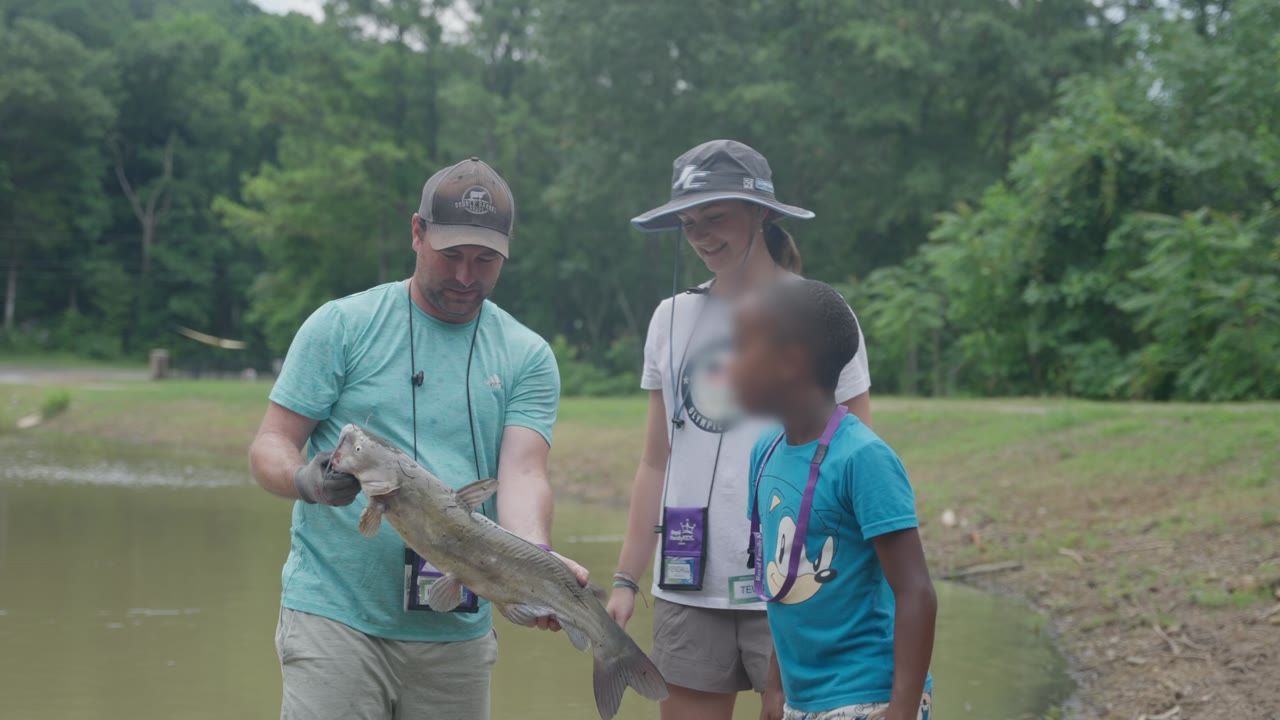 A counselor showing a fish by a pond