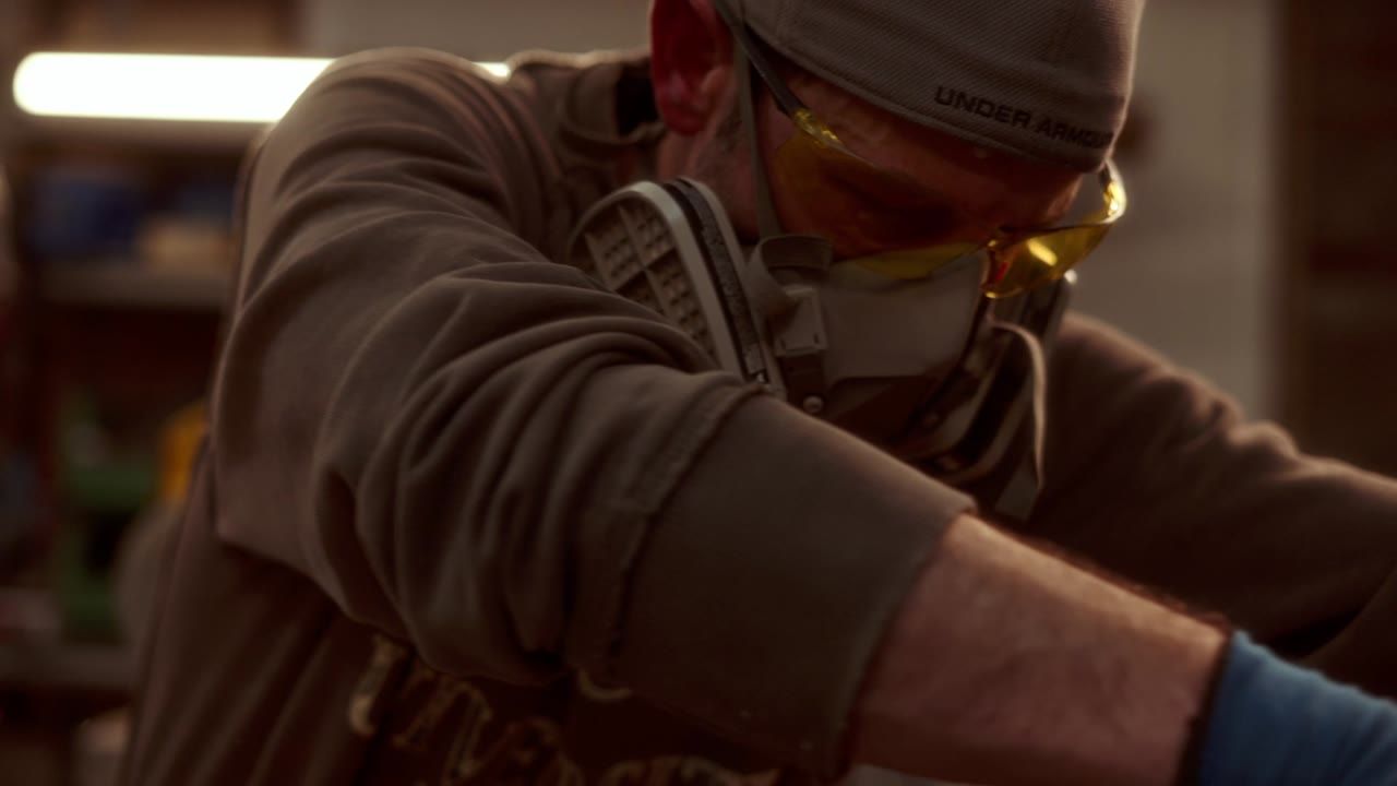 A woodworker in a mask cutting wood