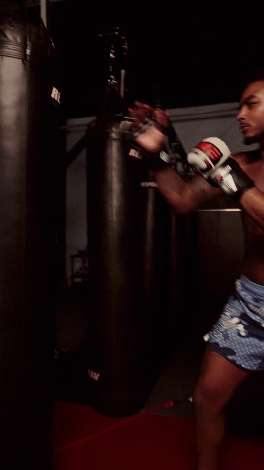 A fighter at a heavy bag in red light