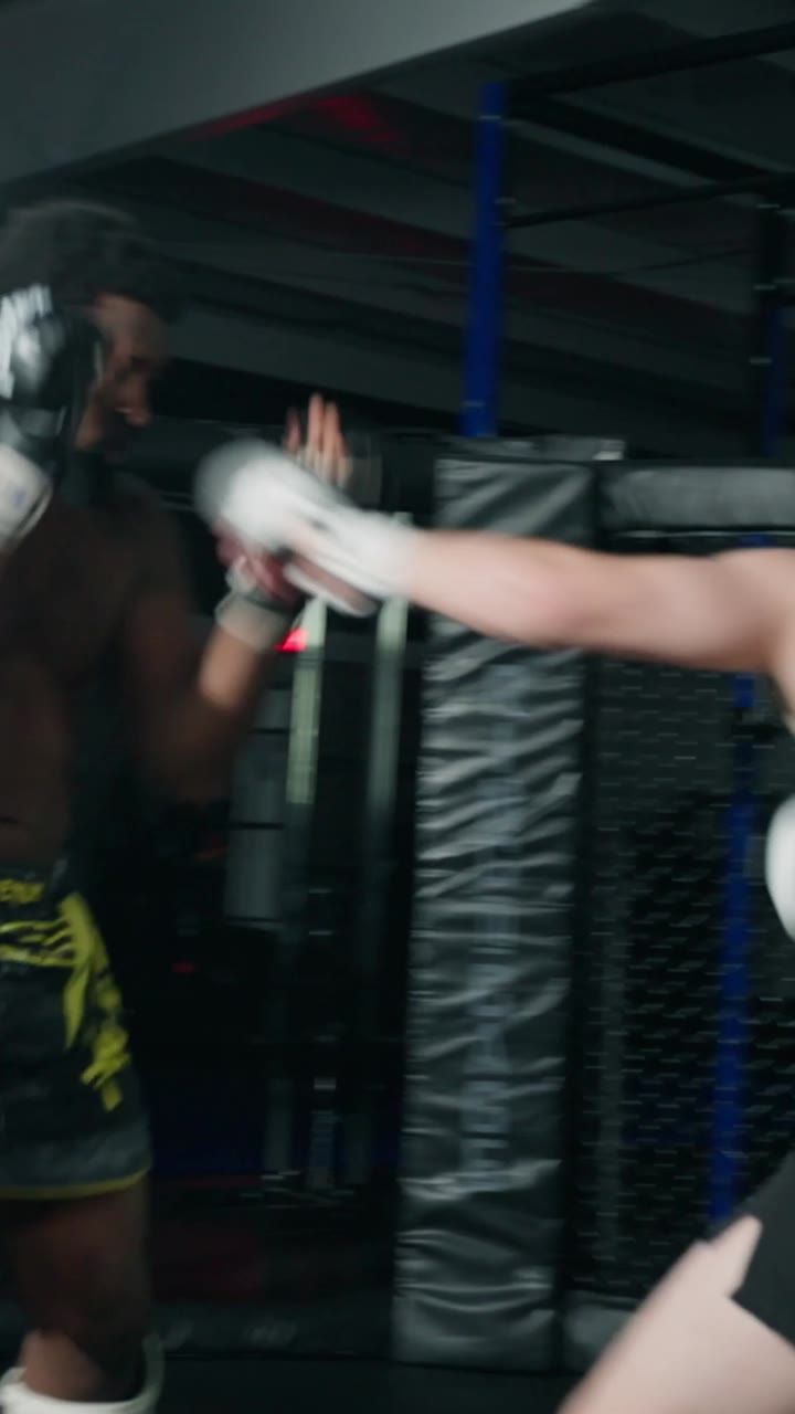 A fighter throwing a kick at pads in a gym