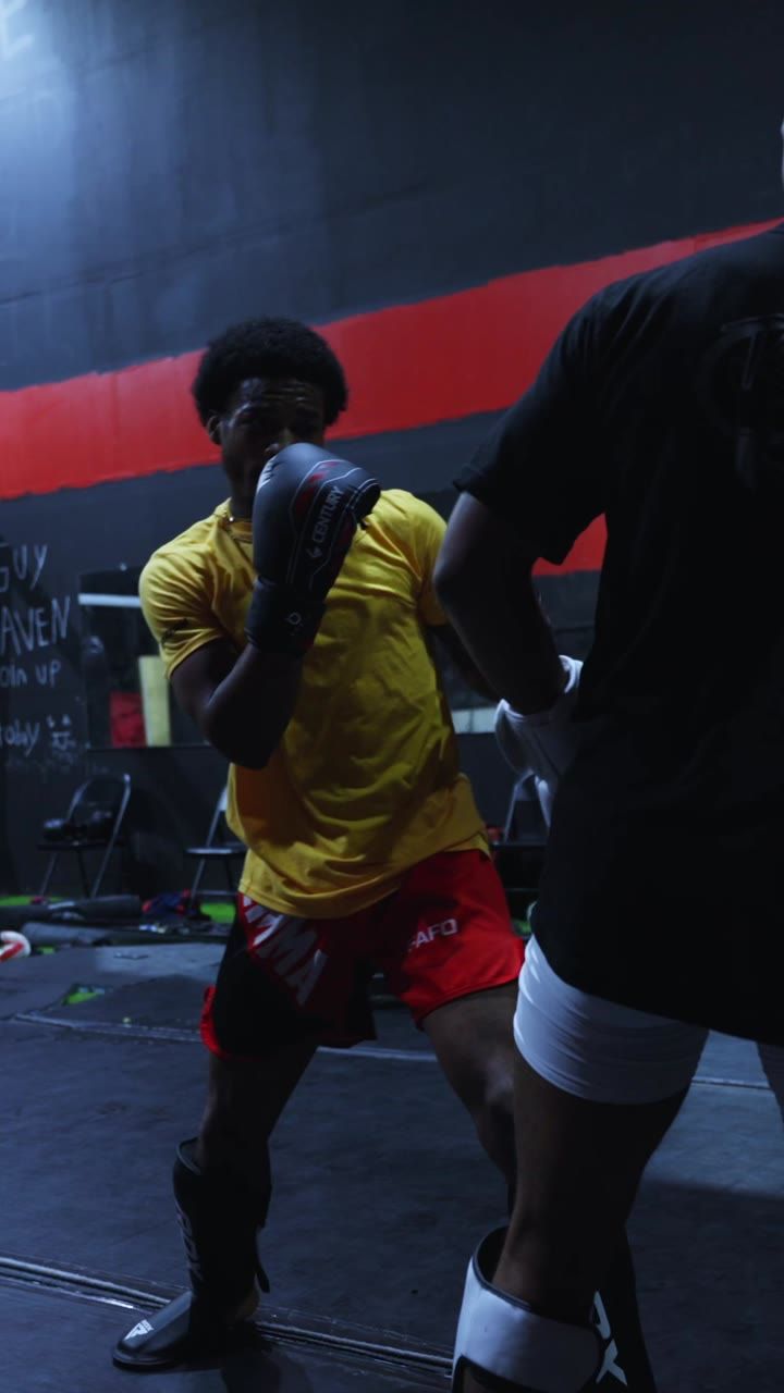 A fighter in a yellow shirt working pads