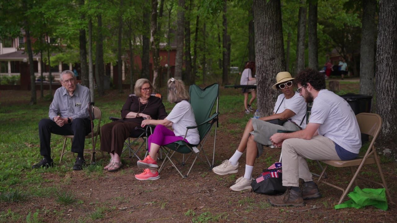People gathered in lawn chairs in the woods