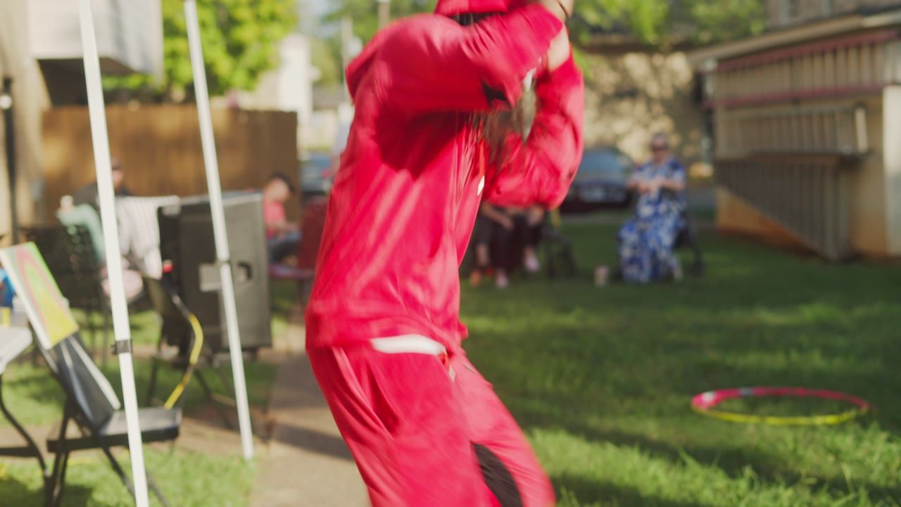 A performer in a red tracksuit dancing at an outdoor block party