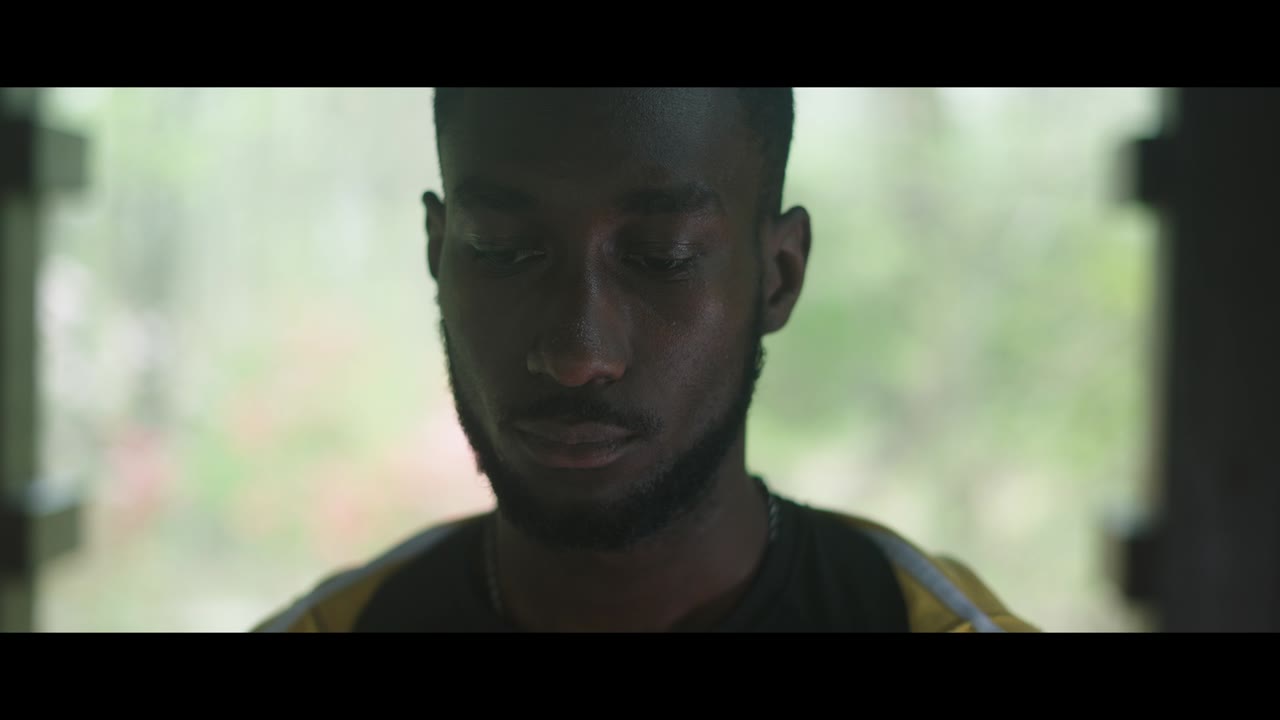 A young man looking down in soft light