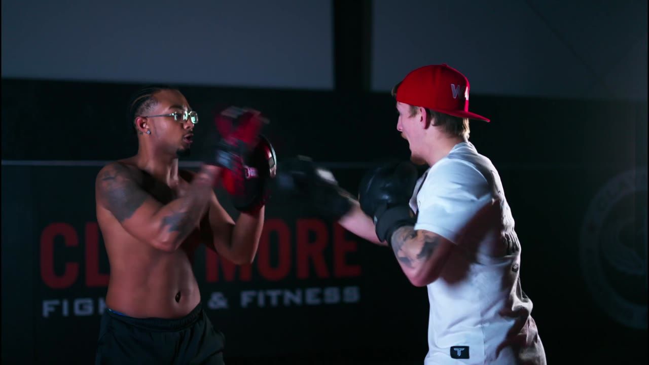 A fighter hitting pads held by a coach