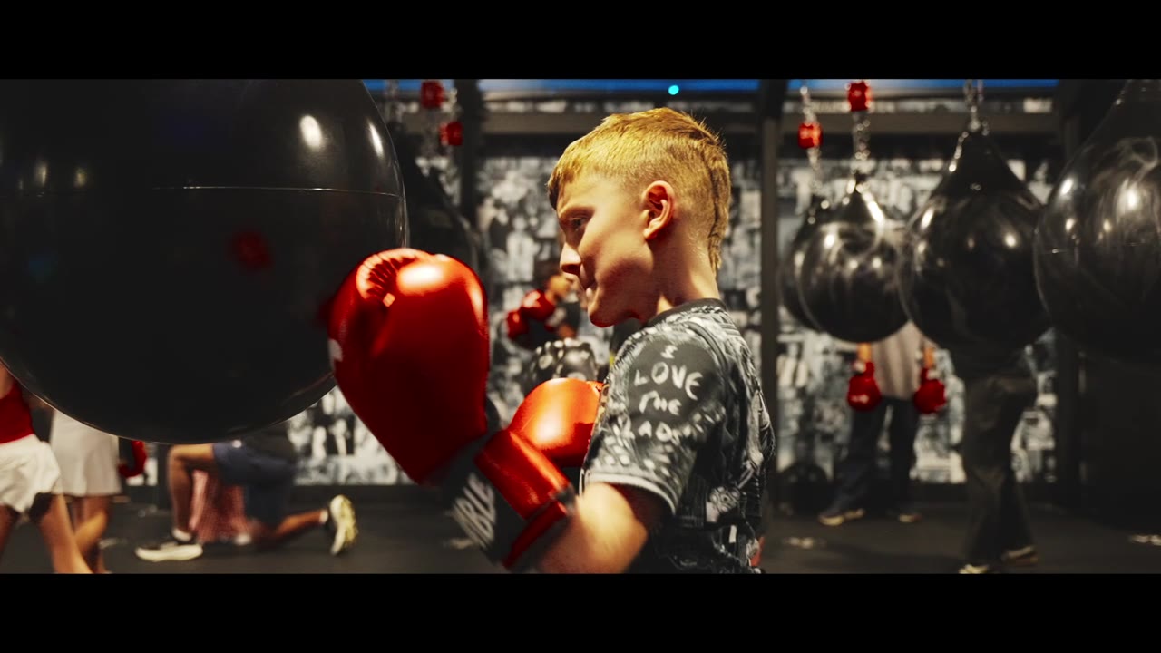 A young boxer in red gloves at a heavy bag