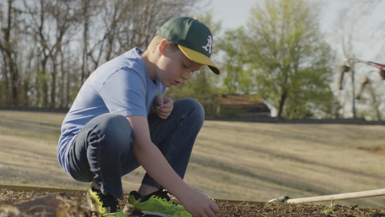 A boy in a cap planting in a garden