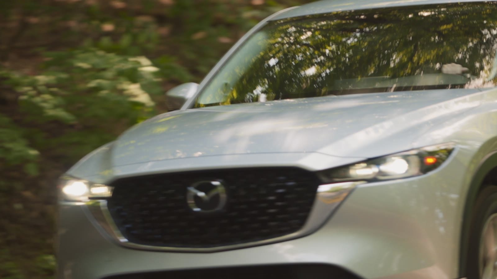 A silver Mazda CX-5 rolling along a wooded road